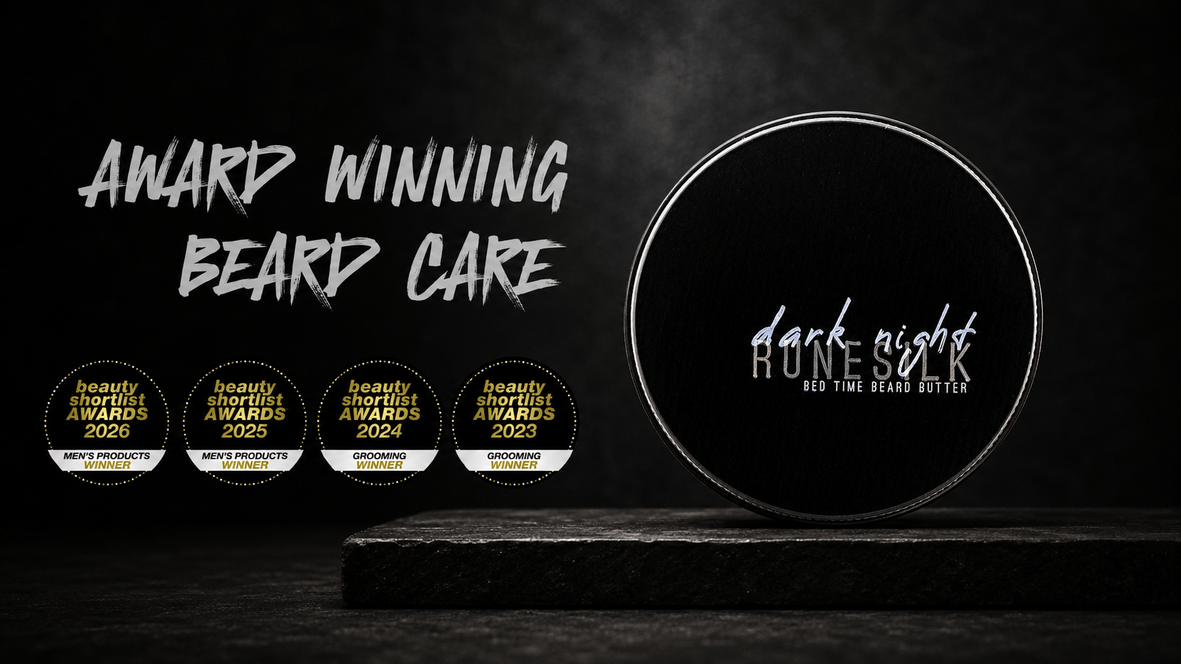 A round black beard care container labelled 'dark night RUNESILK' sits on a dark wooden surface against a black background, with stylized text reading 'AWARD WINNING BEARD CARE' and four award seals along the left side.